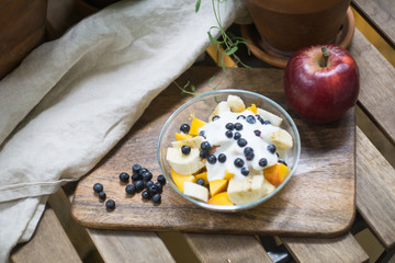 Oatmeal or granola with yogurt and fruits and berries. Peach, mango, banana, blueberry, raspberry apple. On a wooden background. Top view