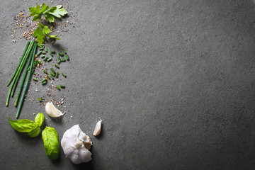 Top Down View On Kitchen Ingredients Like Garlic, Basil, Spices And Herbs On Slate Stone, With Free Space In The Middle And Right Side