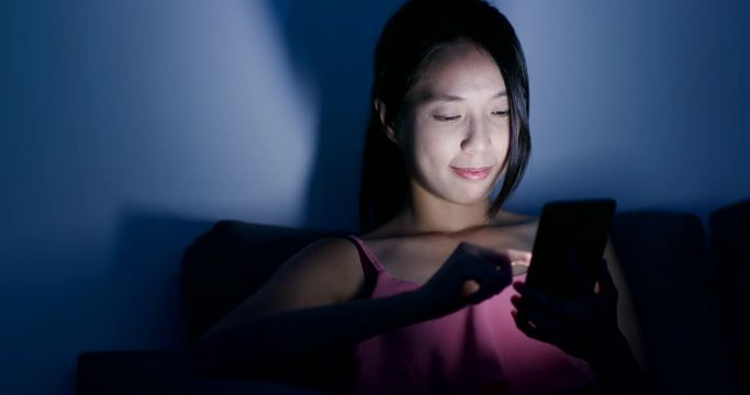 Woman use of mobile phone in the evening at home