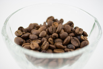 Grains of coffee in a glass bowl  on a white background