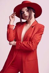 Elegant beautiful woman in a red fashionable suit and wide hat