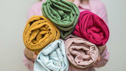 Vertical method of folding clothes KonMari Method. A woman holds clean jeans folded into a roll. 