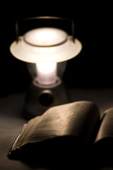Reading an old book at night with the soft light of a lantern 
