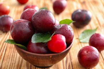 Naklejka na ściany i meble Bowl with ripe juicy plums on wooden table