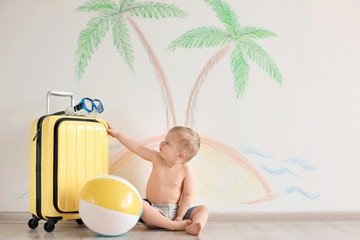 Fototapeta premium Adorable little child playing traveler with suitcase indoors