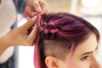 Fototapeta premium Professional stylist braiding woman's color hair in beauty salon. Modern trend