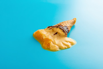 Obraz na płótnie Canvas mini mango or orange flavor ice cream cone melting on blue background
