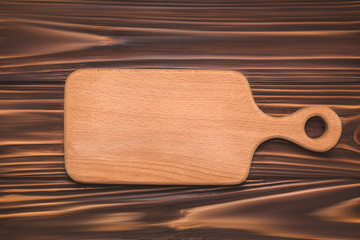 Kitchen cutting board on a wooden background, top view.
