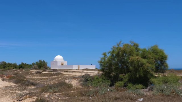 Lonely white stone chapel at sea island on blue sky background