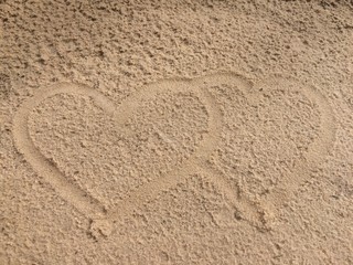 Draw two hearts together on the sand beach.