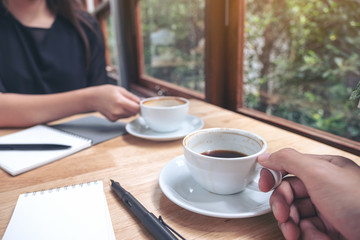 Closeup image of two businessman drinking coffee while talking and meeting in office