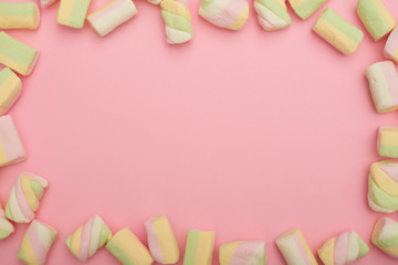Frame made of marshmallows on pink flatlay