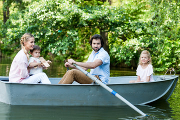 side view of young family riding boat on river at park