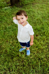 high angle view of adorable little kid standing on green grass and looking at camera