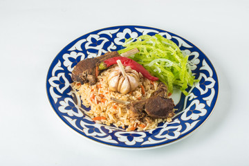 Traditional asian mutton pilaf served with fresh salad on ornamental plate