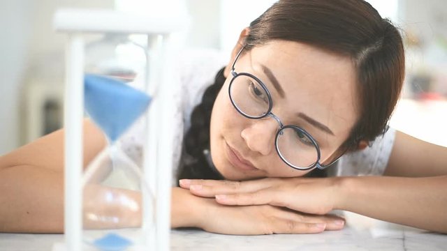Young woman looking at hourglass in home