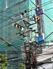 Large steel eletric support with a lot of tangled wires, cables. On the pole there is a step-down transformer. Complete confusion and mess