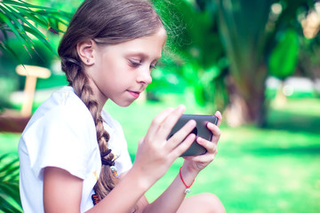 Technology and people concept - happy smiling girl using smartphone outdoors