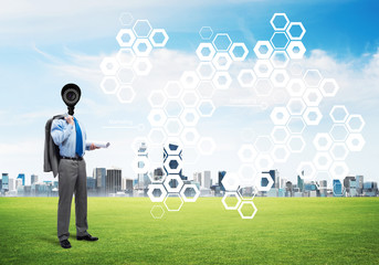 Camera headed man standing on green grass against modern cityscape