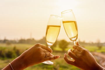 Two beautiful asian women toss white wine of champange in with warm sunset light