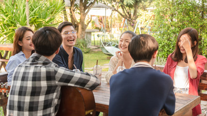 Group of friends hang out in cafe play guitar and sing also use smartphone play social media