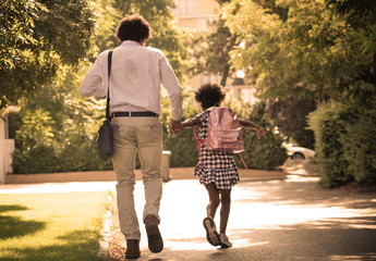 Father and daughter running trough park.