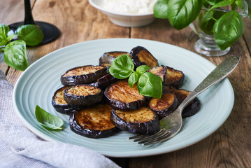 Fried eggplant slices with basil on a plate                               