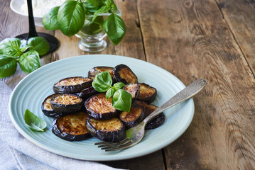 Fried eggplant slices with basil on a plate                               