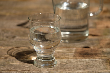 Edles Wasserglas (rund) mit Kanne im Hintergrund