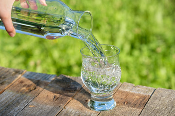 Karaffe giesst Wasser in Glas (Garten)