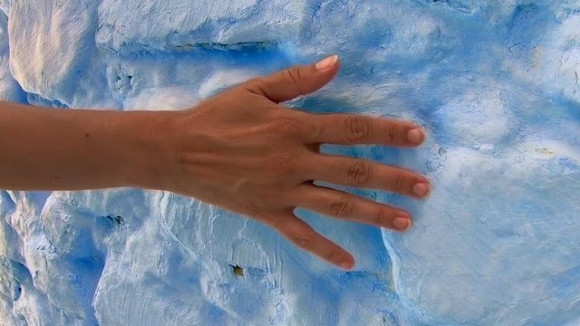 Woman walks and grazes hand on blue wall in Morocco.
