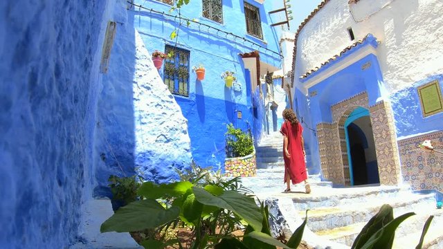 Woman with djellaba in Chefchouen street, famous blue city. Traditional moroccan architectural details