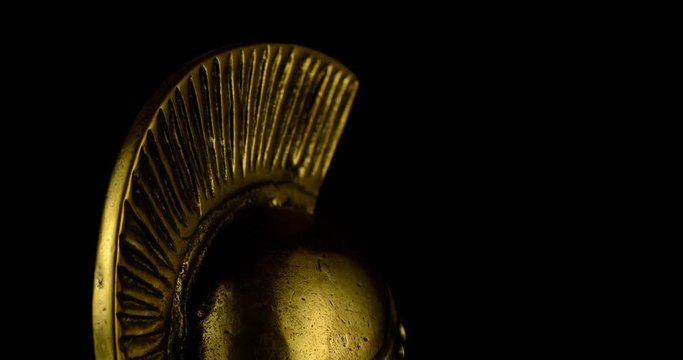A wonderful golden Spartan helmet as part of the equipment of ancient greek soldiers. King Leonidas and his 300th The piece of metal stands against a black background