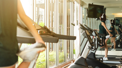 Woman stretching legs on running machine with reflection in window prepare for run in side of a gym