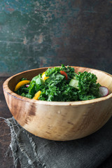 Kale salad in wooden bowl on rustic background