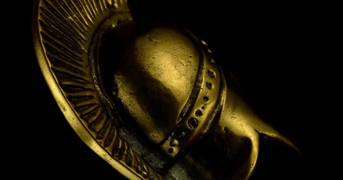 A wonderful golden Spartan helmet as part of the equipment of ancient greek soldiers. King Leonidas and his 300th The piece of metal stands against a black background