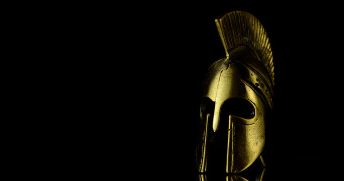 A wonderful golden Spartan helmet as part of the equipment of ancient greek soldiers. King Leonidas and his 300th The piece of metal stands against a black background
