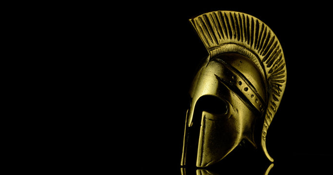 A wonderful golden Spartan helmet as part of the equipment of ancient greek soldiers. King Leonidas and his 300th The piece of metal stands against a black background