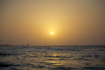 Obraz premium Beautiful sunset at the beach, amazing colors, light beam shining through the cloudscape. Azerbaijan sea and beach . The sound of the sea waves is coming . The fisherman fishes in the sea .