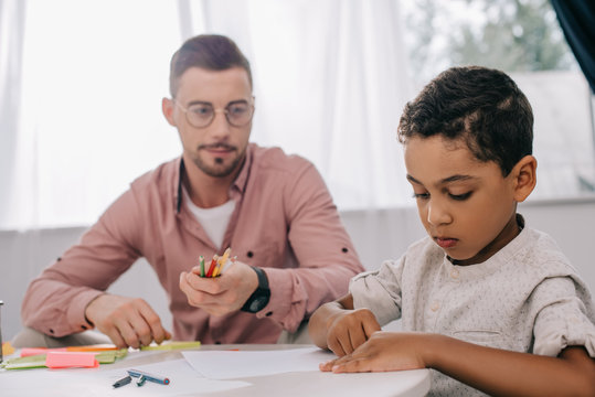 caucasian teacher and african american boy drawing picture together in classroom