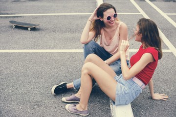 Woman friends sitting on the ground and talking together