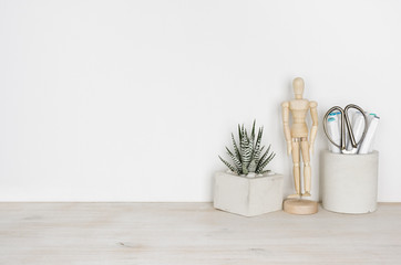 Fototapeta na wymiar Wooden desktop with flower pot, human statuette and office supplies