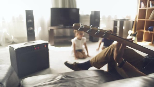 Father plays electric guitar with his children