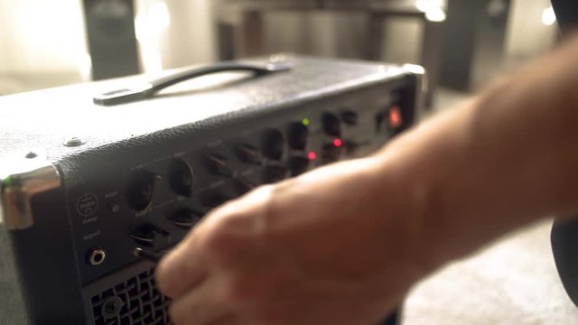 The guy connects the guitar to the amplifier