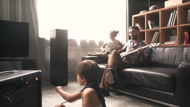 Father plays electric guitar with his children