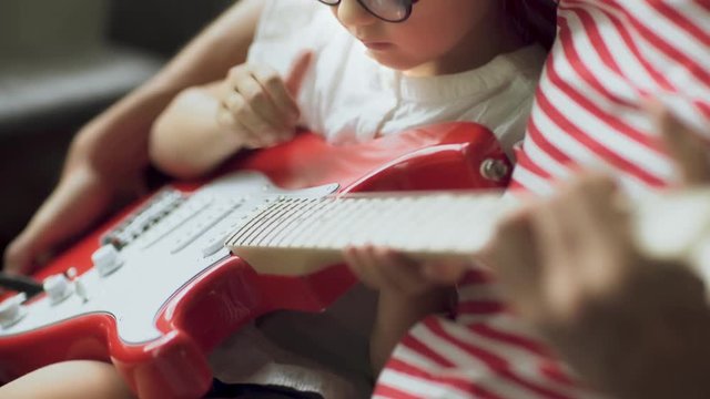 Father teaches a little daughter to play electric guitar
