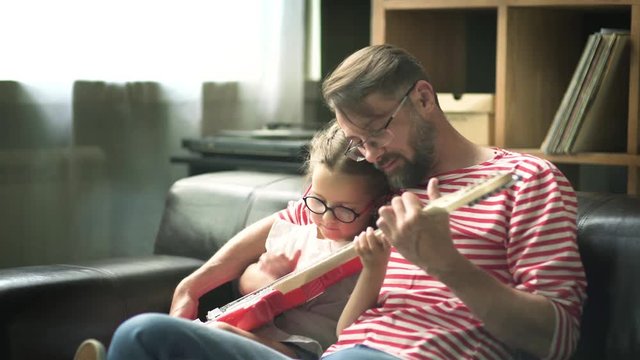 Father teaches a little daughter to play electric guitar