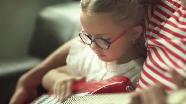 Father teaches a little daughter to play electric guitar