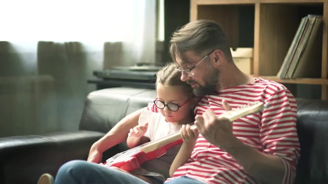 Father teaches a little daughter to play electric guitar