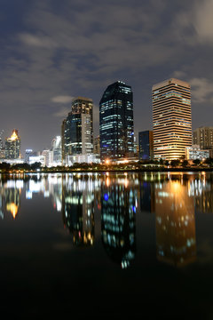 Modern buildings of Benchakitti Park with lights reflection in night city